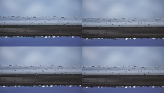 不锈钢扶手上的雨滴映衬着模糊的大海背景。特写镜头。雨露的水滴聚集在闪闪发光的铬钢杆扶手上高清在线视频素材下载