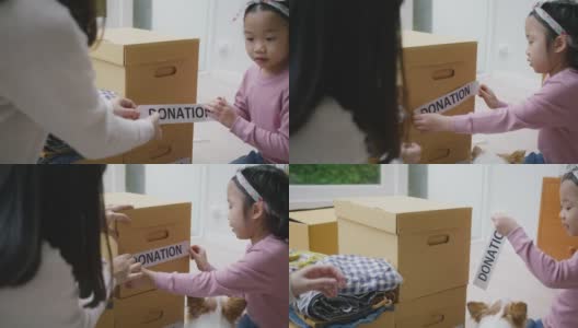 亚洲妈妈和孩子准备在家里捐赠旧衣服包装盒。高清在线视频素材下载