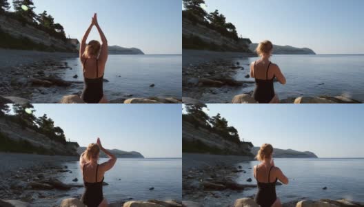 一个在海边练瑜伽的白人女人。清晨穿着黑色泳衣冥想的女孩。瑜伽和个人活动的概念。冥想，冷静和健康的生活方式。在户外放松高清在线视频素材下载