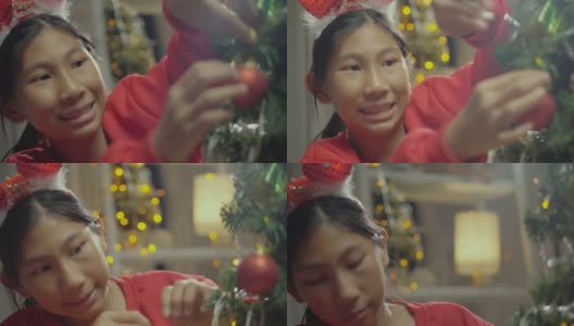 快乐的亚洲男孩穿着红色的毛衣和发带装饰圣诞树在晚上的时间在家里，节日的概念。高清在线视频素材下载