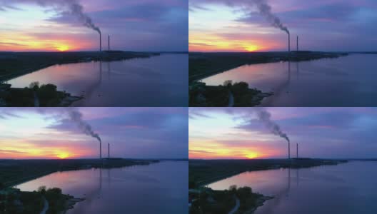 以美丽的自然为背景的烟管。晚上河边有有害的生产。夕阳西下时，工业附近的蓝色水和天空。鸟瞰图。高清在线视频素材下载