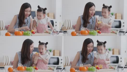 家庭单身母亲和女儿享受和快乐的烹饪在干净的厨房。家长帮助孩子制作水果和蔬菜沙拉的视频教程从平板电脑。通过视频电话学习自制烹饪。高清在线视频素材下载