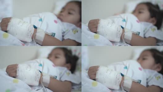 生病的亚洲女孩包扎手的特写，而躺在医院的床上。治疗室实时拍摄。高清在线视频素材下载