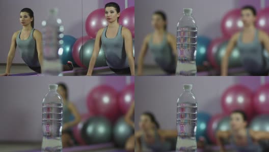 从柔韧的女人在健身房做伸展运动到一瓶新鲜的水高清在线视频素材下载