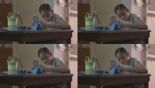 亚洲可爱的女孩使用手机和数字平板电脑在做作业期间在线上课。女青少年在家通过视频电话学习。高清在线视频素材下载