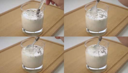 将粘稠的酸乳或酸奶与奇亚籽混合在玻璃杯中，放在木砧板上。高清在线视频素材下载