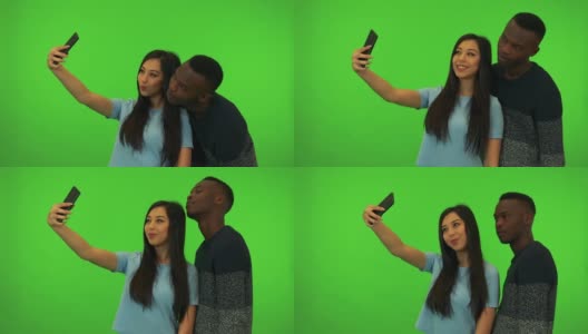 一名年轻的亚洲女子和一名年轻的黑人男子在绿幕摄影棚自拍高清在线视频素材下载