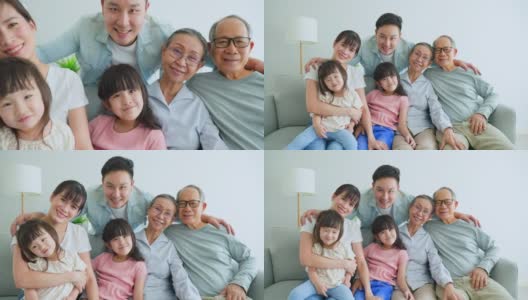 全家福亚洲大家庭一起在家里度过快乐时光。几代人，老夫妇和年轻的父母带着小孩子坐在沙发上微笑，看着客厅里的摄像机。高清在线视频素材下载