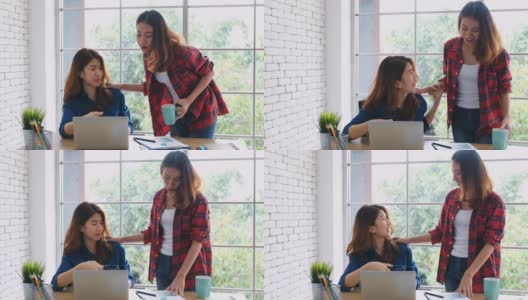 两个年轻的亚洲女性工作与笔记本电脑和喝咖啡在家庭办公室与幸福，办公室休闲的生活方式高清在线视频素材下载