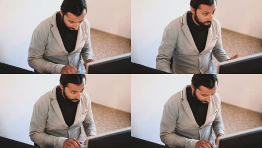 一个留着胡子，穿着夹克在电脑前工作的人高清在线视频素材下载