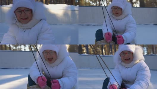 小女孩骑着雪橇。女孩很喜欢坐雪橇。女孩笑着和表情从快速滑雪橇。冬天孩子们的娱乐。高清在线视频素材下载