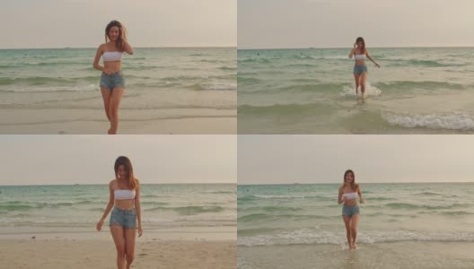 在沙滩上跑步的亚洲女人。年轻快乐的女性在比基尼放松和有趣的热带海时，日落而度假，夏季旅行的概念。慢动作镜头。高清在线视频素材下载