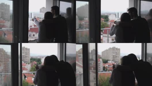 幸福的夫妇拥抱，同时看着他们的新公寓的窗户高清在线视频素材下载