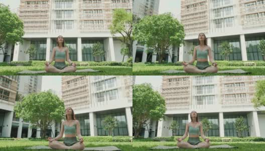 年轻的亚洲女人在运动服坐在瑜伽户外绿色公园。健康，运动，健身和生活方式的概念。瑜伽和冥想对健康有好处高清在线视频素材下载