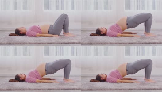 亚洲年轻孕妇呼吸冥想瑜伽半桥姿势，年轻健康孕妇瑜伽冥想放松舒适的白色舒适的家，瑜伽运动的健康概念高清在线视频素材下载