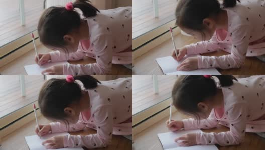 混血亚洲女孩坐在地板上，在家学习写字，在家学习教育高清在线视频素材下载