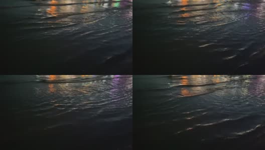 夜晚，海浪在水面上荡漾，反射着鲜艳的彩灯。高清在线视频素材下载