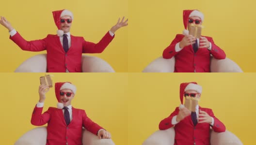 一个快乐的小胡子男人，穿着红色的衣服，戴着圣诞老人帽，戴着红色滑稽的眼镜，对着相机微笑，在黄色的背景上捕捉圣诞礼物。新年销售和促销概念高清在线视频素材下载