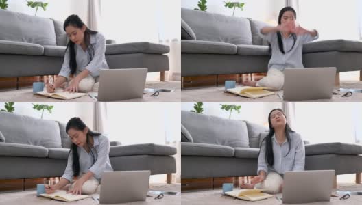 年轻的亚洲女商人正在笔记本上写一个新的项目。她累了，伸懒腰，躺在客厅的沙发上。在家工作，商业女性和工作理念。高清在线视频素材下载
