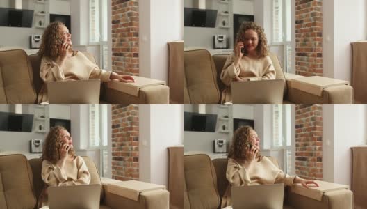 一个美丽开朗的女孩坐在客厅的沙发上讲电话时，使用了一台银色的笔记本电脑。和朋友交流。在线培训高清在线视频素材下载