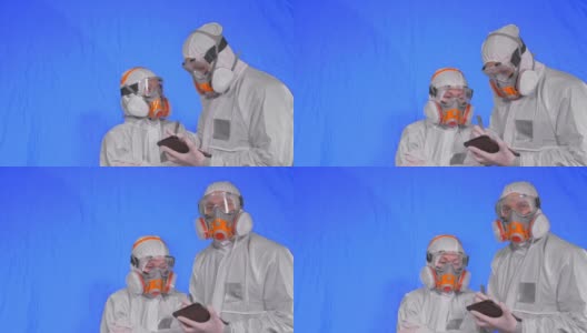 呼吸器中的科学家病毒学家用手写笔在平板电脑中书写。男男女女都戴着医用防护口罩色度键蓝色。高清在线视频素材下载