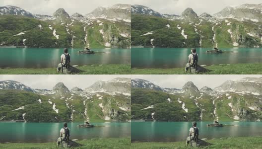 女徒步旅行者看风景，蓝色的湖在阿尔卑斯山上高清在线视频素材下载