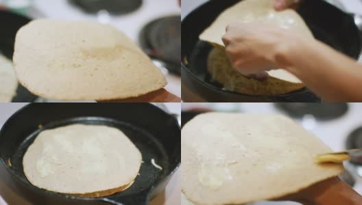 一名白人妇女的手用餐刀在玉米饼上涂上黄油，然后把它放在炉灶上的铸铁煎锅里油炸玉米饼上高清在线视频素材下载