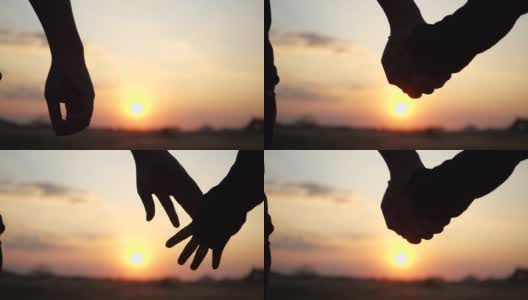 一对恋人在4K慢镜头中牵手。男人和女人的剪影牵手在日落背景。情侣信任，爱和情人节的概念。高清在线视频素材下载