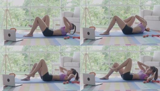 健身女性锻炼，仰卧起坐，锻炼腹肌，坐起坐下，听从笔记本电脑的指导。美丽的亚洲女人在体育。高清在线视频素材下载