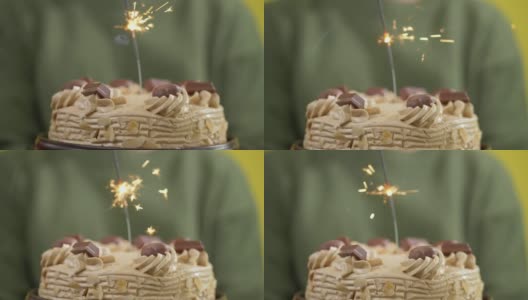 男孩拿着生日蛋糕与闪闪发光的黄色背景，庆祝节日的概念。高清在线视频素材下载