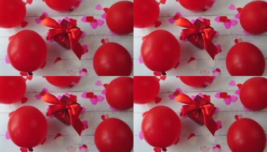 白色的木桌上放着心形和气球，是一个红色的情人节礼盒高清在线视频素材下载