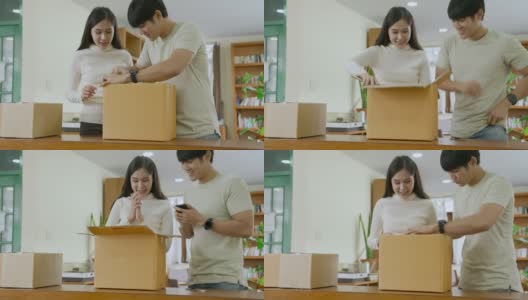 亚洲夫妇从网上零售店打开纸箱或包裹，用手机拍下照片高清在线视频素材下载