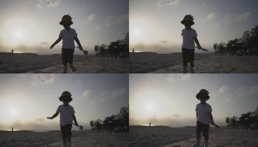 小男孩在夕阳下的沙滩上玩沙子。高清在线视频素材下载