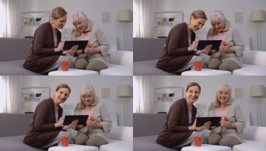 老年妇女微笑着，在平板电脑上看娱乐节目，快速互联网高清在线视频素材下载