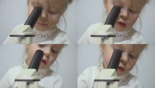 一个小女孩在一堵白墙旁边玩显微镜。高清在线视频素材下载