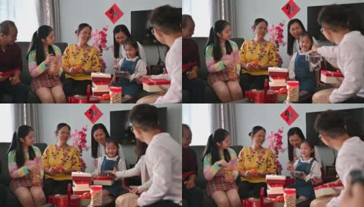 欢乐的亚洲家庭三代欢聚在客厅庆祝中国新年，享受传统美食高清在线视频素材下载