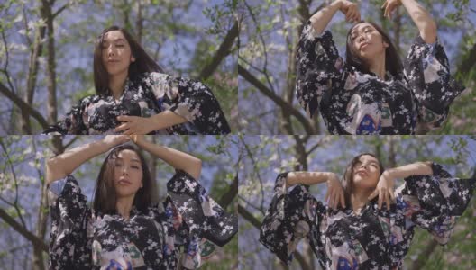 美丽的亚洲女人看着相机在春天盛开的公园慢动作跳舞。美丽的日本女舞者穿着和服，在户外阳光下跳舞。高清在线视频素材下载