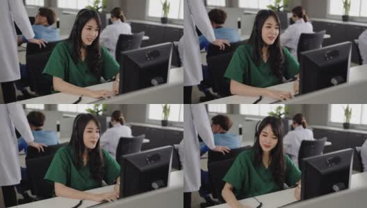亚洲护士在呼叫中心办公室的电脑上对病人进行远程保健咨询。高清在线视频素材下载