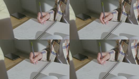一个男人的手在笔记本上做笔记的特写，脸部是看不见的高清在线视频素材下载