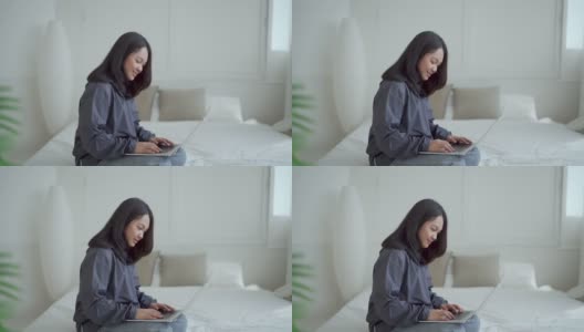 4k, Portrait，一个可爱的亚洲少女。穿着灰色衬衫躺在床上，带着笔记本电脑在卧室里开心地上网学习高清在线视频素材下载