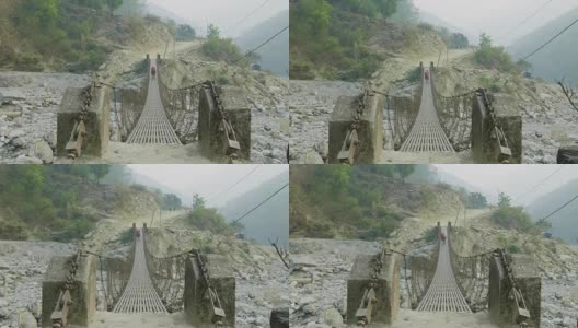 两名背包客在尼泊尔的一座悬空金属桥上行走。高清在线视频素材下载