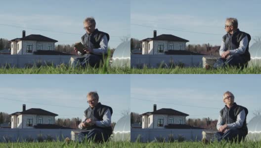 一位戴眼镜的老人低低地坐在绿色草地上的长凳上。高清在线视频素材下载