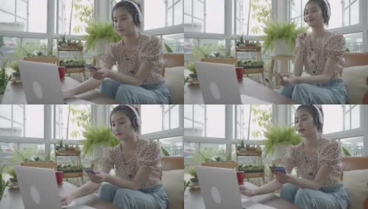 新冠肺炎疫情发生后，年轻的亚洲女性在被隔离期间在家客厅网购，在温室的小花园中放松，在室内花园的概念高清在线视频素材下载