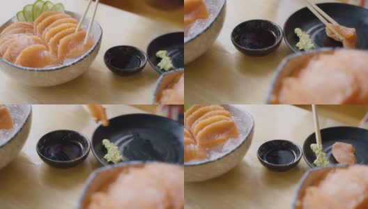 用筷子夹紧手挑三文鱼生鱼片在日本餐馆里蘸着大豆和芥末。高清在线视频素材下载