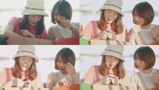 两个年轻的亚洲女人在地铁上展示她们在购物袋里买的新东西，慢镜头高清在线视频素材下载