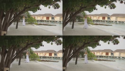 初见新婚夫妇。新娘在一个浪漫的热带小岛上，在蔚蓝的泻湖海洋附近的白色沙滩上举行婚礼高清在线视频素材下载
