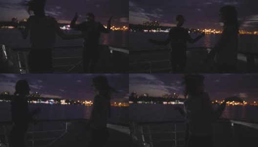 夜晚，两个美丽的年轻女子在甲板上跳舞的剪影。船上的闺蜜高清在线视频素材下载