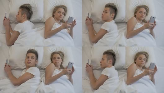 一对年轻夫妇背靠背躺在床上用手机上网，漠不关心高清在线视频素材下载