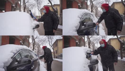 老人戴着防护口罩，用塑料刮冰器和扫把清理车窗上的积雪高清在线视频素材下载