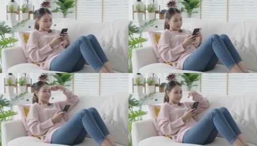 年轻迷人美丽随意的亚洲女性在沙发上看手机玩社交媒体高清在线视频素材下载